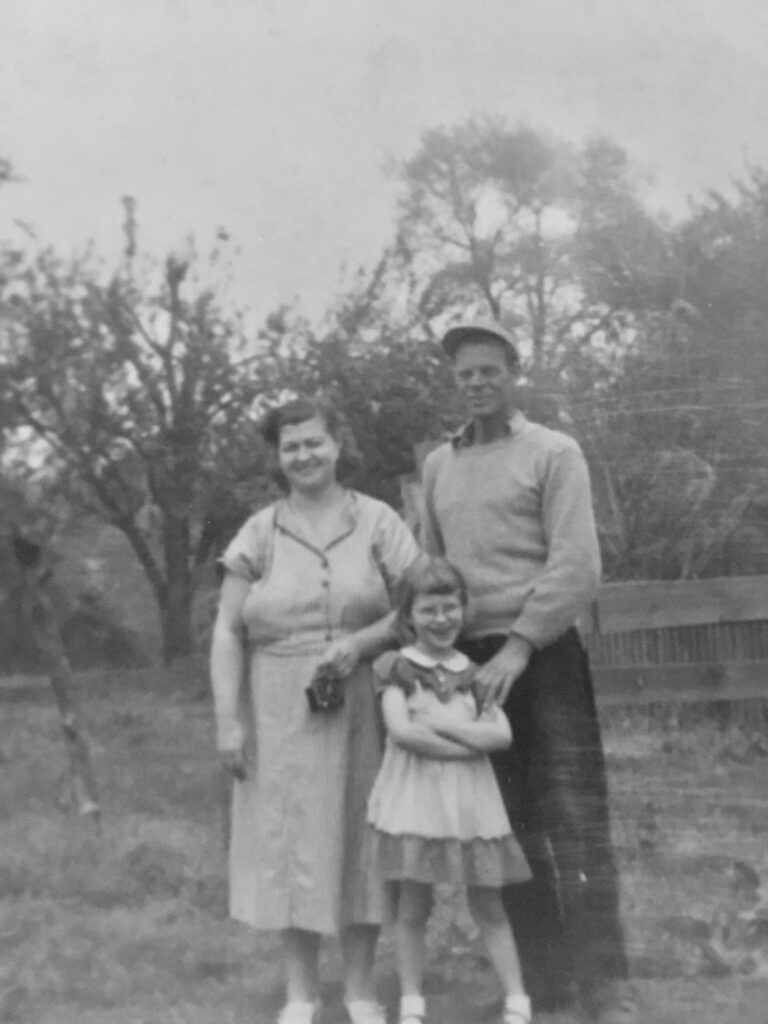 Black-and-white family photograph of Mamaw and Granddaddy standing with their young daughter in a garden, circa 1948.