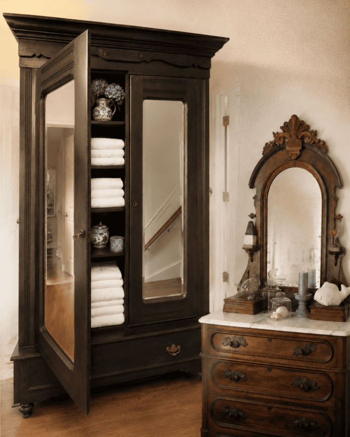 Antique dark-wood wardrobe displayed beside its matching marble-top dresser and ornate mirror.